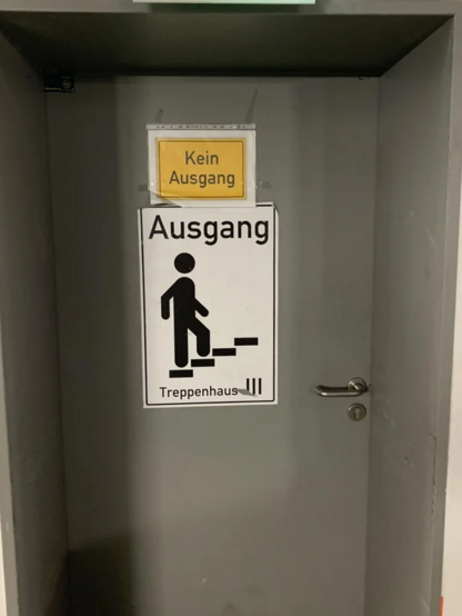 eine Tiefgaragen Tür mit einem gelben "Kein Ausgang" schild und ein "AUsgang - Treppenhaus" schild